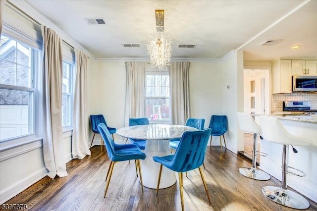 dining space with an inviting chandelier, dark wood-type flooring, and ornamental molding