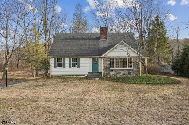 view of front of house featuring entry steps, a shingled roof, stone siding, a front lawn, and a chimney