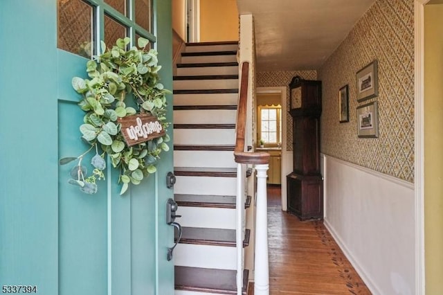 stairway featuring wallpapered walls, a wainscoted wall, and wood finished floors