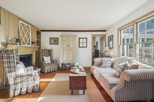 living area featuring a fireplace with raised hearth, wood finished floors, and baseboards