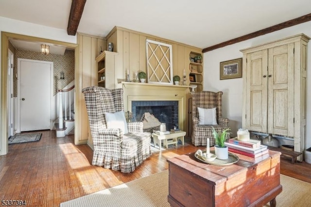 living area featuring a fireplace, beamed ceiling, and hardwood / wood-style floors