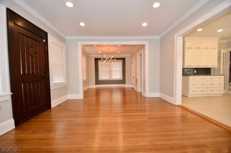 entrance foyer featuring crown molding, light wood-type flooring, and a chandelier