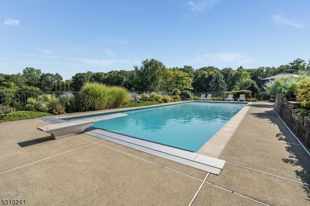 view of pool with a diving board and a patio area