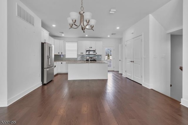 kitchen with visible vents, dark wood finished floors, appliances with stainless steel finishes, backsplash, and a notable chandelier