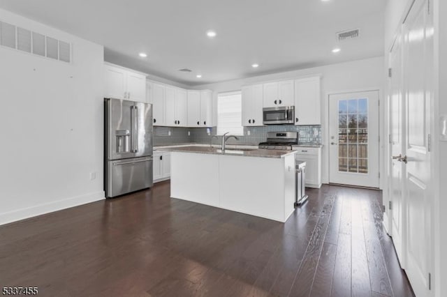 kitchen featuring tasteful backsplash, visible vents, dark wood finished floors, stainless steel appliances, and white cabinetry