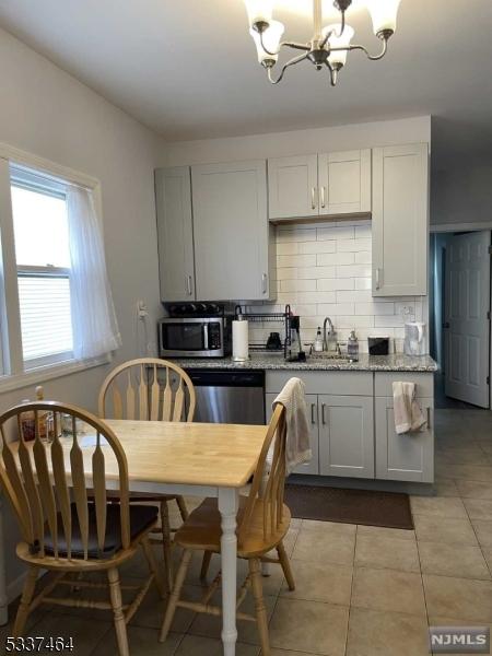 kitchen with stainless steel appliances, light stone countertops, sink, and white cabinets