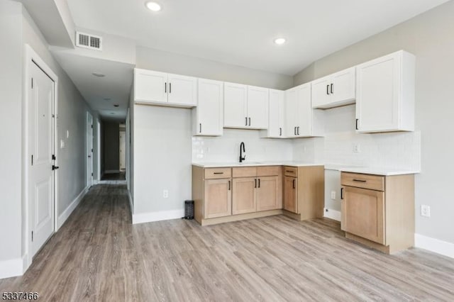 kitchen with white cabinetry, light hardwood / wood-style floors, sink, and decorative backsplash