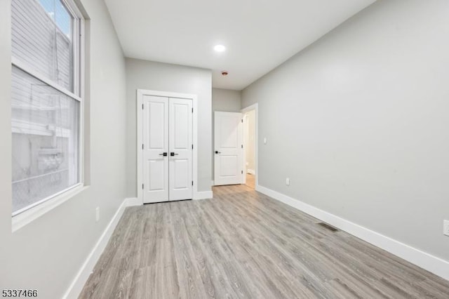 unfurnished bedroom featuring light hardwood / wood-style flooring and a closet