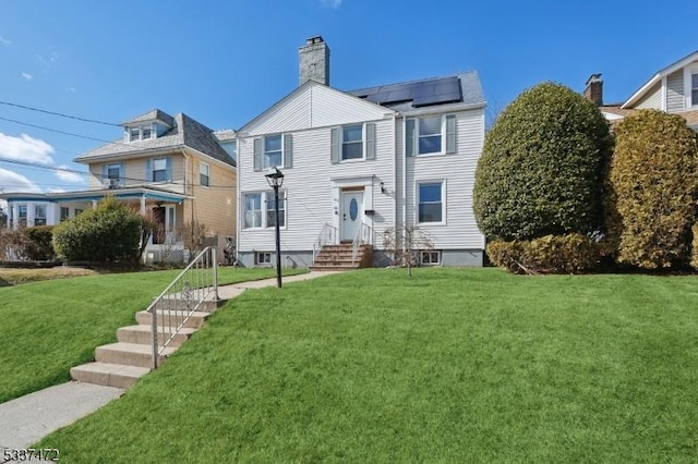 view of front of home with solar panels and a front yard