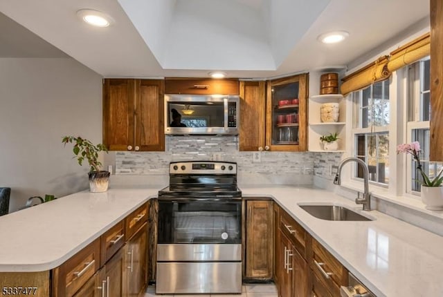 kitchen with sink, decorative backsplash, stainless steel appliances, and kitchen peninsula