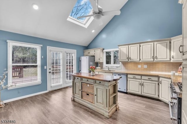 kitchen featuring appliances with stainless steel finishes, a skylight, light wood-style flooring, and a center island