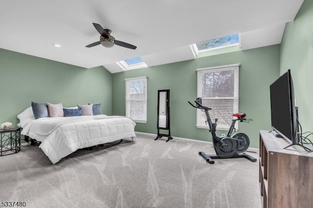 bedroom with lofted ceiling with skylight, baseboards, a ceiling fan, and light colored carpet