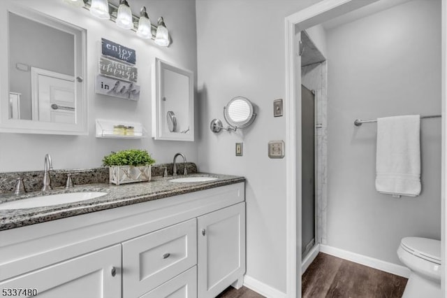 bathroom with a stall shower, a sink, baseboards, and wood finished floors