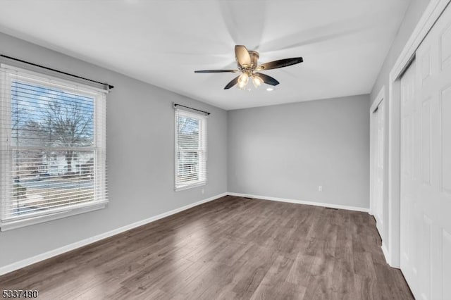 unfurnished bedroom featuring dark wood-style flooring, ceiling fan, and baseboards