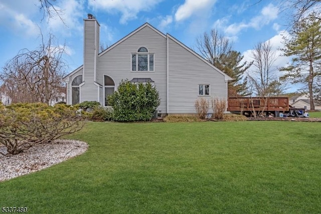 rear view of house with a chimney, a yard, and a deck