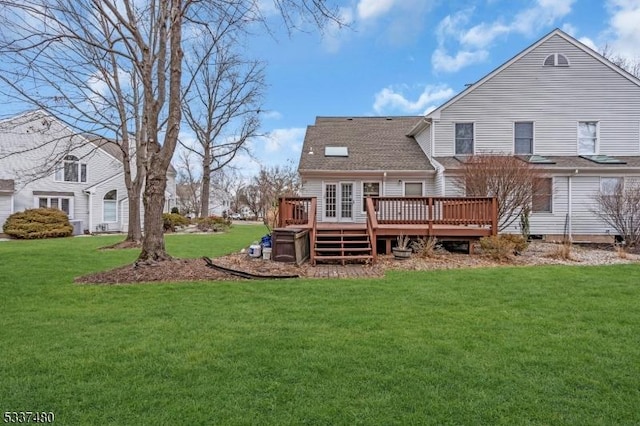 back of property with a yard, roof with shingles, and a wooden deck