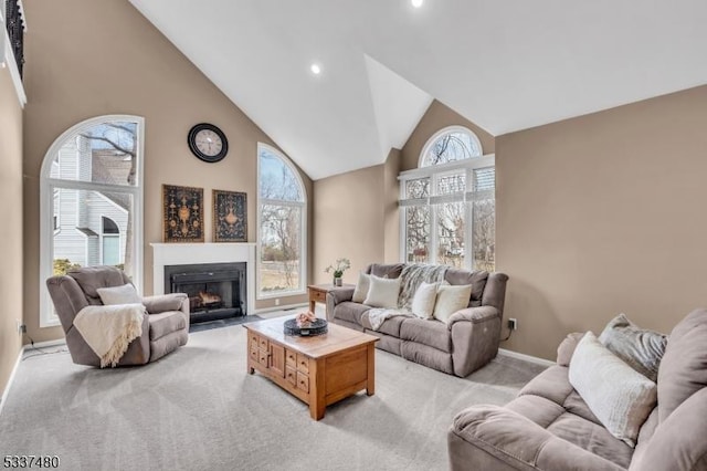 living area featuring high vaulted ceiling, recessed lighting, light carpet, a fireplace with flush hearth, and baseboards