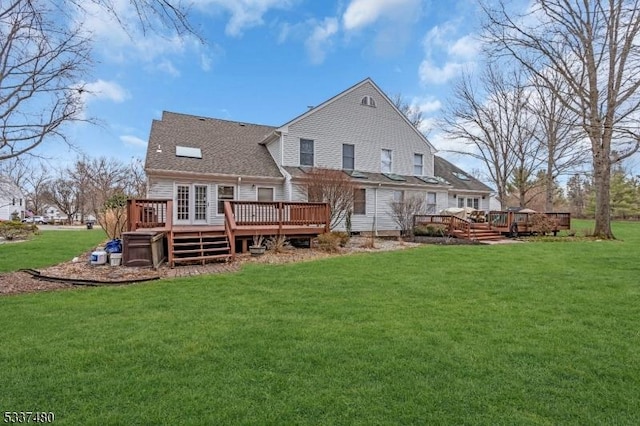 back of property featuring a shingled roof, a yard, and a wooden deck