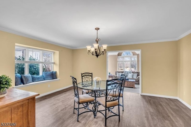 dining area featuring an inviting chandelier, crown molding, baseboards, and wood finished floors