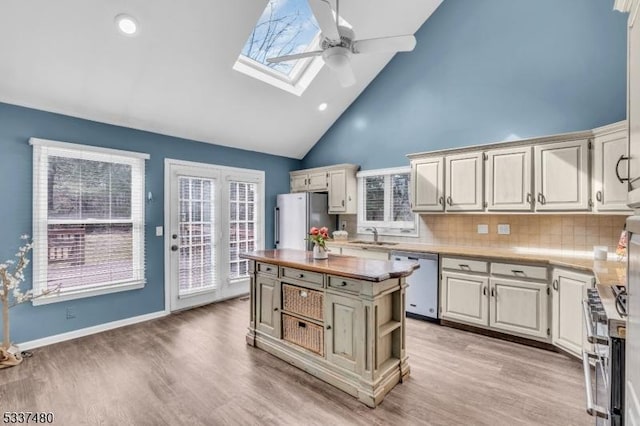 kitchen with stainless steel appliances, a skylight, a kitchen island, open shelves, and light wood finished floors