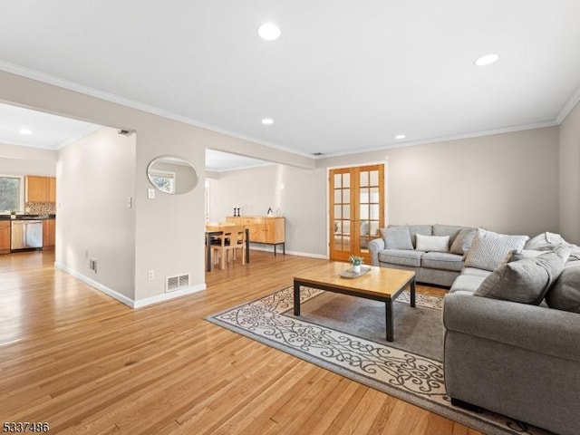 living room with french doors, ornamental molding, and light hardwood / wood-style flooring