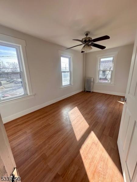 unfurnished bedroom featuring radiator heating unit, baseboards, ceiling fan, and dark wood-style flooring