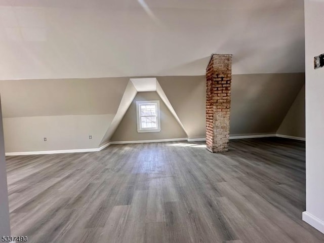 additional living space featuring vaulted ceiling, baseboards, and wood finished floors