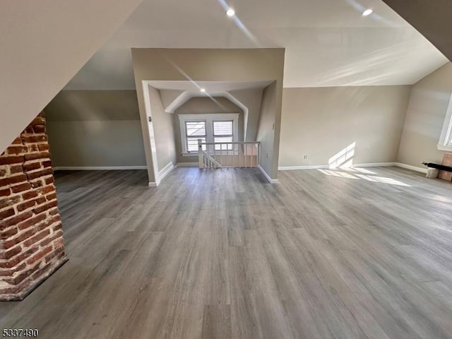 additional living space with vaulted ceiling, wood finished floors, and baseboards