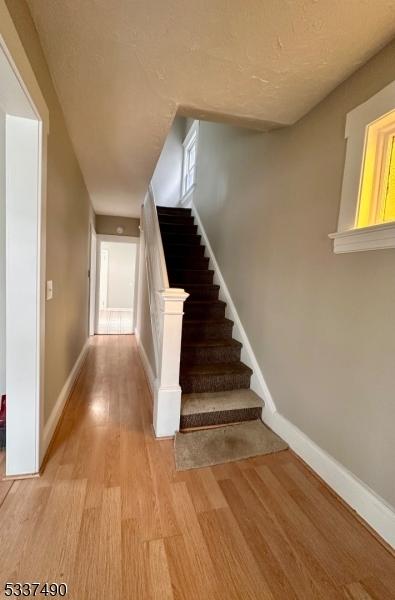 stairway with a textured ceiling, baseboards, and wood finished floors