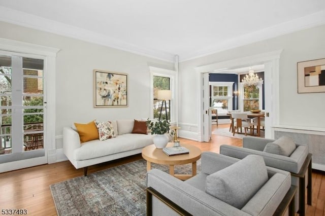 living room with a notable chandelier, radiator heating unit, a healthy amount of sunlight, and hardwood / wood-style floors