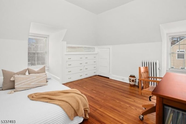 bedroom featuring hardwood / wood-style flooring, lofted ceiling, and radiator heating unit