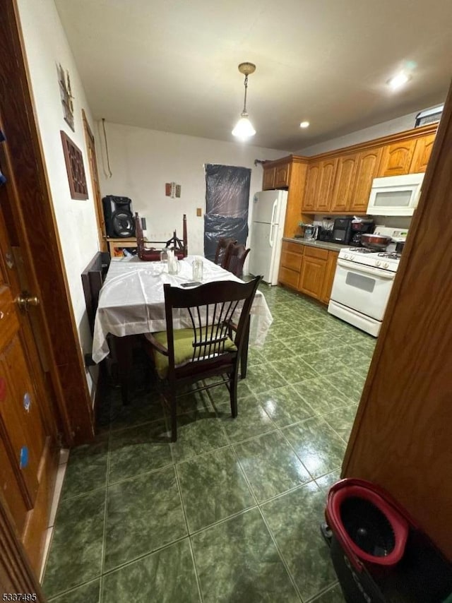 kitchen featuring white appliances, decorative light fixtures, and dark tile patterned floors