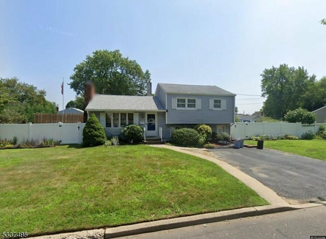 split level home featuring a gate, fence, driveway, and a front lawn