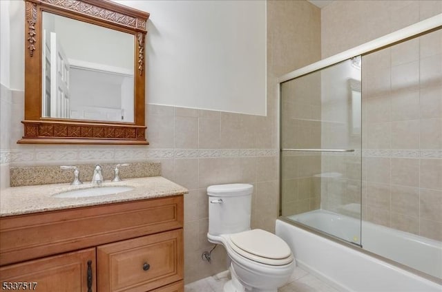 full bathroom featuring vanity, tile walls, toilet, and enclosed tub / shower combo