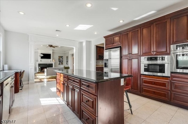 kitchen featuring dark stone countertops, a kitchen bar, light tile patterned flooring, a kitchen island, and stainless steel appliances