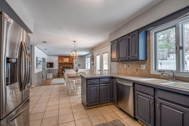 kitchen featuring sink, gray cabinetry, kitchen peninsula, pendant lighting, and stainless steel appliances