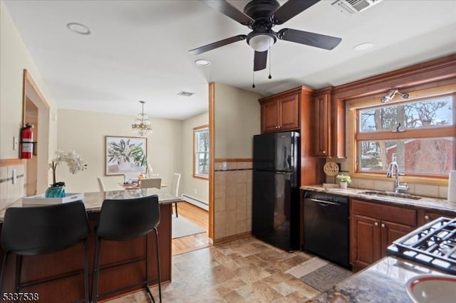 kitchen with a breakfast bar, sink, a baseboard radiator, pendant lighting, and black appliances