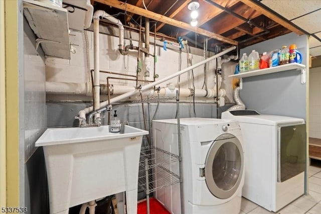 washroom with washing machine and dryer, sink, and light tile patterned flooring