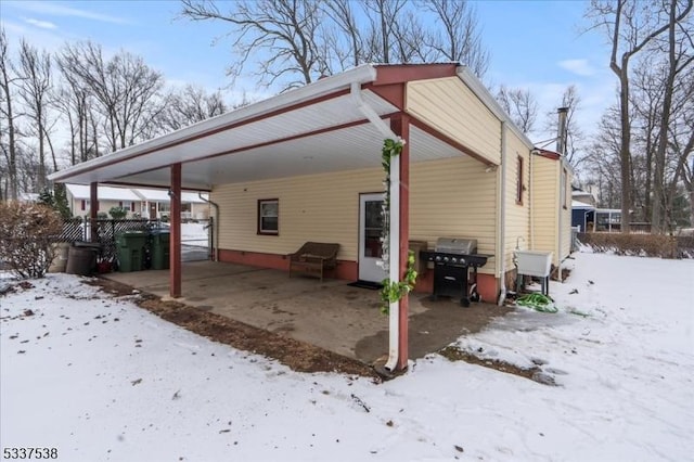 snow covered rear of property with a carport