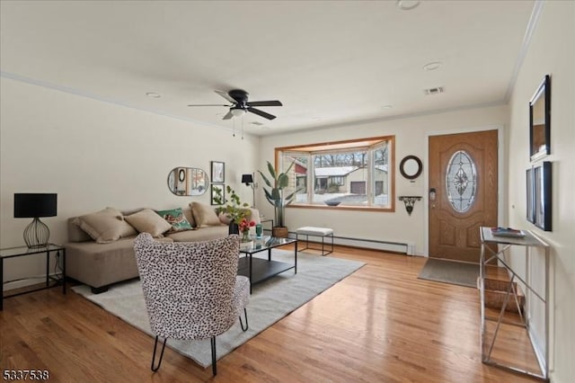 living room featuring ceiling fan, ornamental molding, light wood-type flooring, and a baseboard heating unit