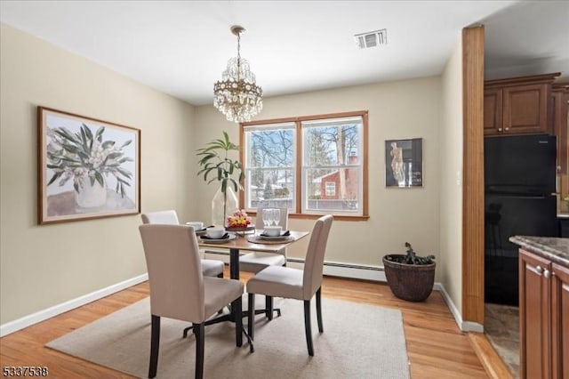 dining room with a notable chandelier, baseboard heating, and light hardwood / wood-style flooring