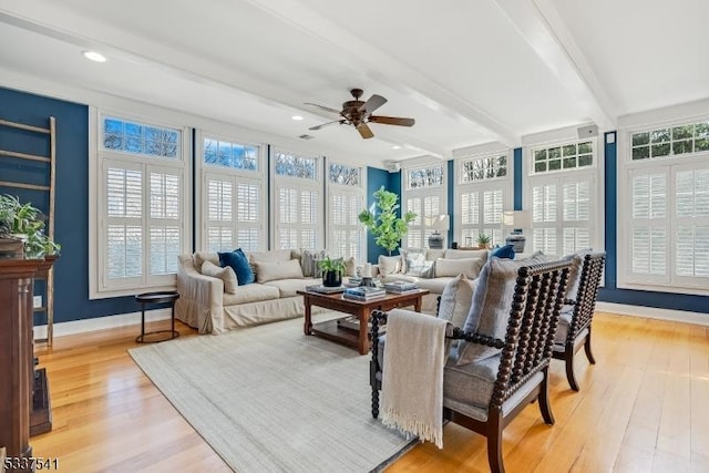 sunroom with plenty of natural light, a ceiling fan, and beamed ceiling