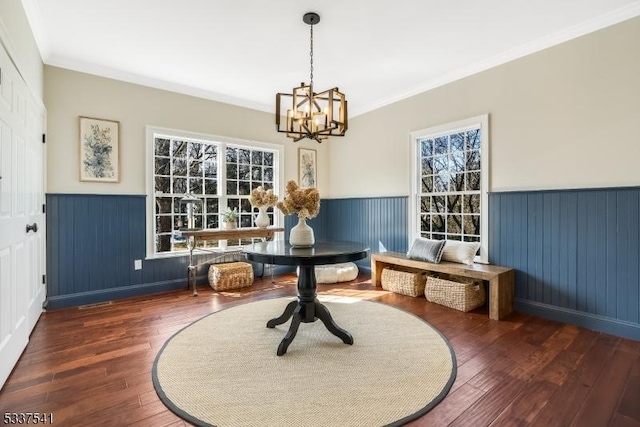 dining space featuring a wainscoted wall, a notable chandelier, dark wood finished floors, and crown molding