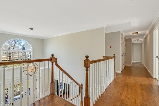 hall featuring baseboards, ornamental molding, wood finished floors, an upstairs landing, and a chandelier