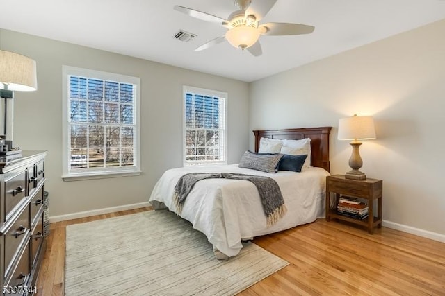 bedroom with light wood-style floors, baseboards, visible vents, and a ceiling fan