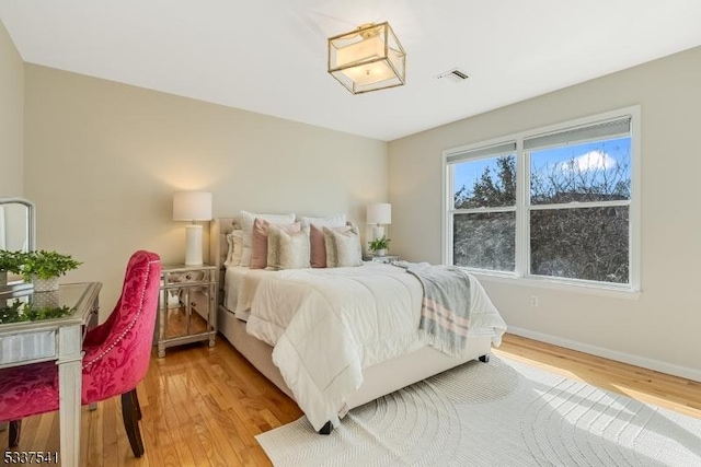 bedroom featuring visible vents, baseboards, and wood finished floors