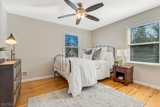 bedroom featuring a ceiling fan, baseboards, visible vents, and light wood finished floors