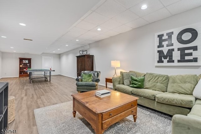 living area featuring light wood finished floors, baseboards, a drop ceiling, and recessed lighting