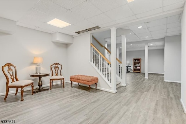 living area with a paneled ceiling, recessed lighting, baseboards, stairs, and light wood finished floors