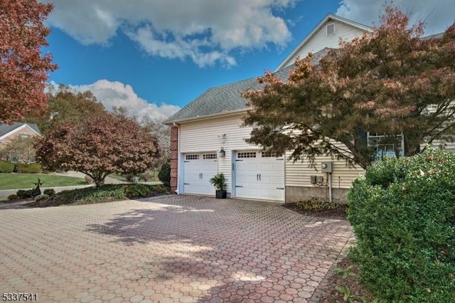 view of side of home with an attached garage and decorative driveway